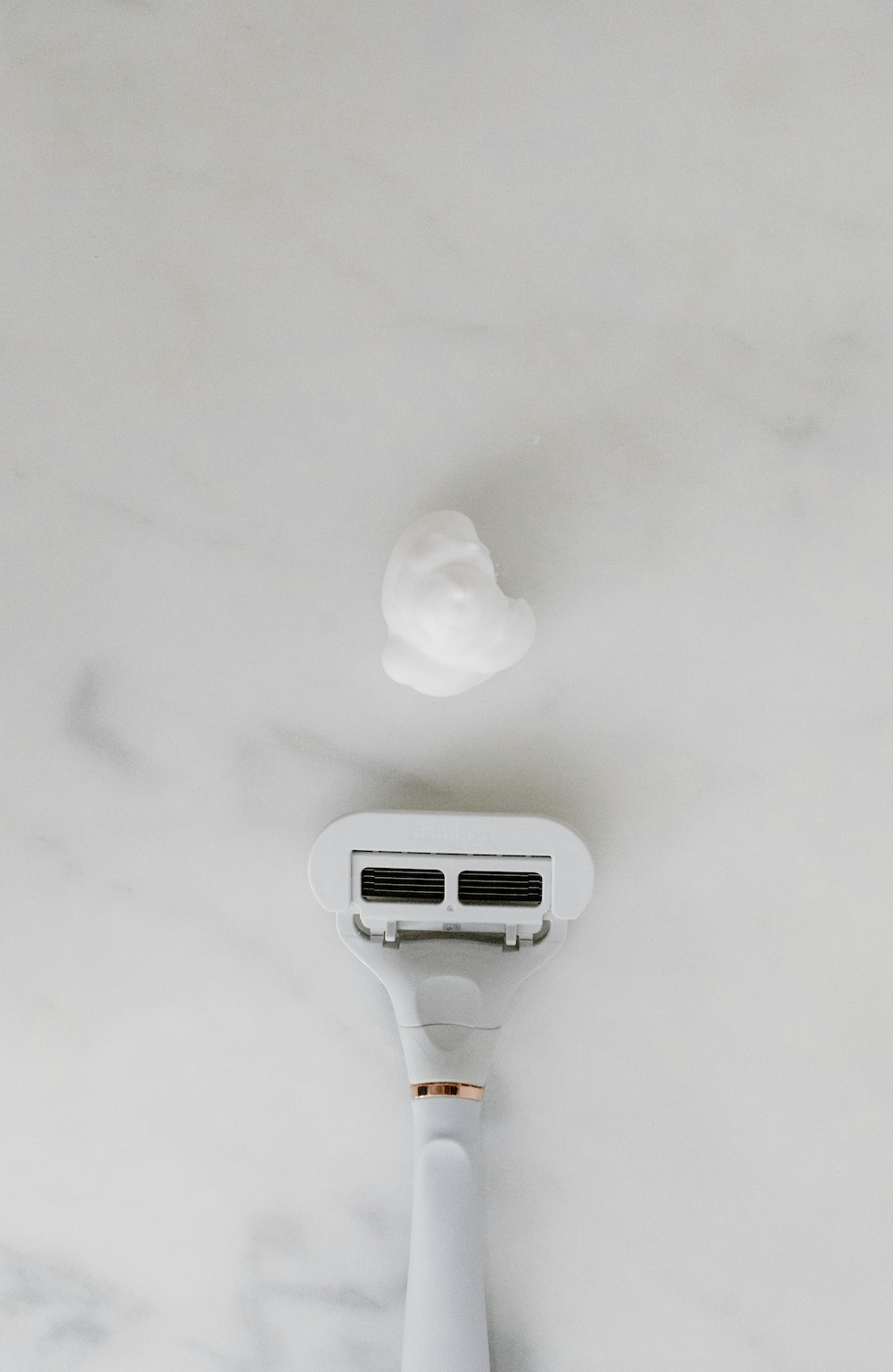 women's shaving essentials razor and cream on bathroom counter